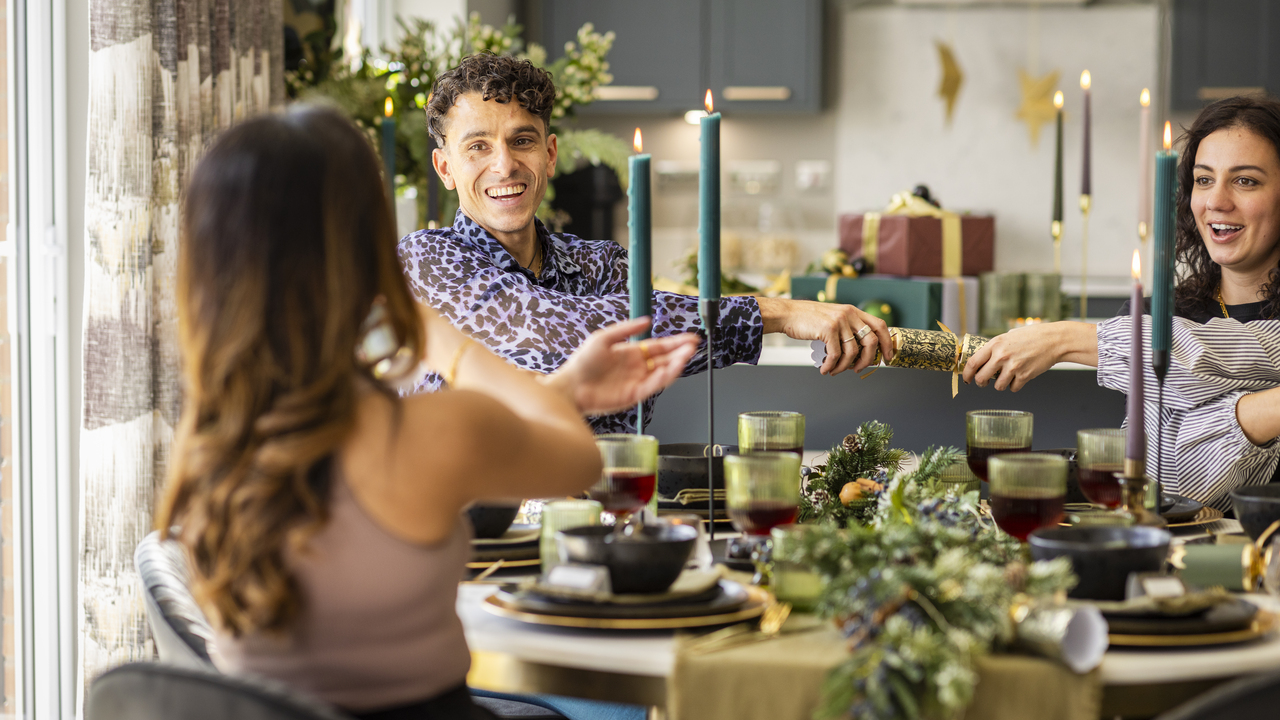 Friends pulling Christmas crackers at the dining table