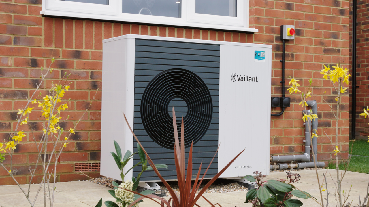 Air source heat pump in a back garden, with yellow flowers on either side