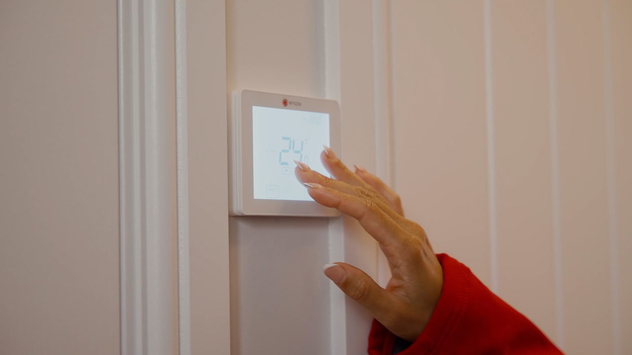 Hand pressing the touch screen on a thermostat