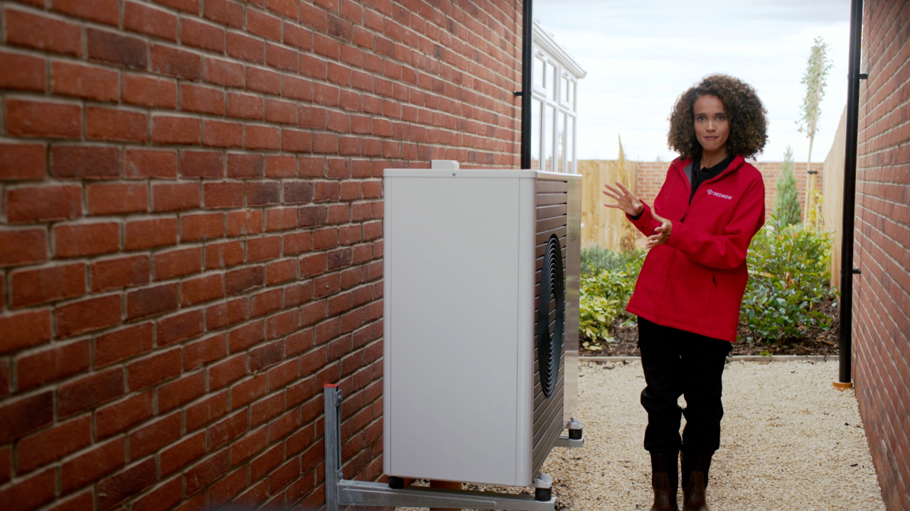 Redrow consultant stood next to an Air Source Heat Pump